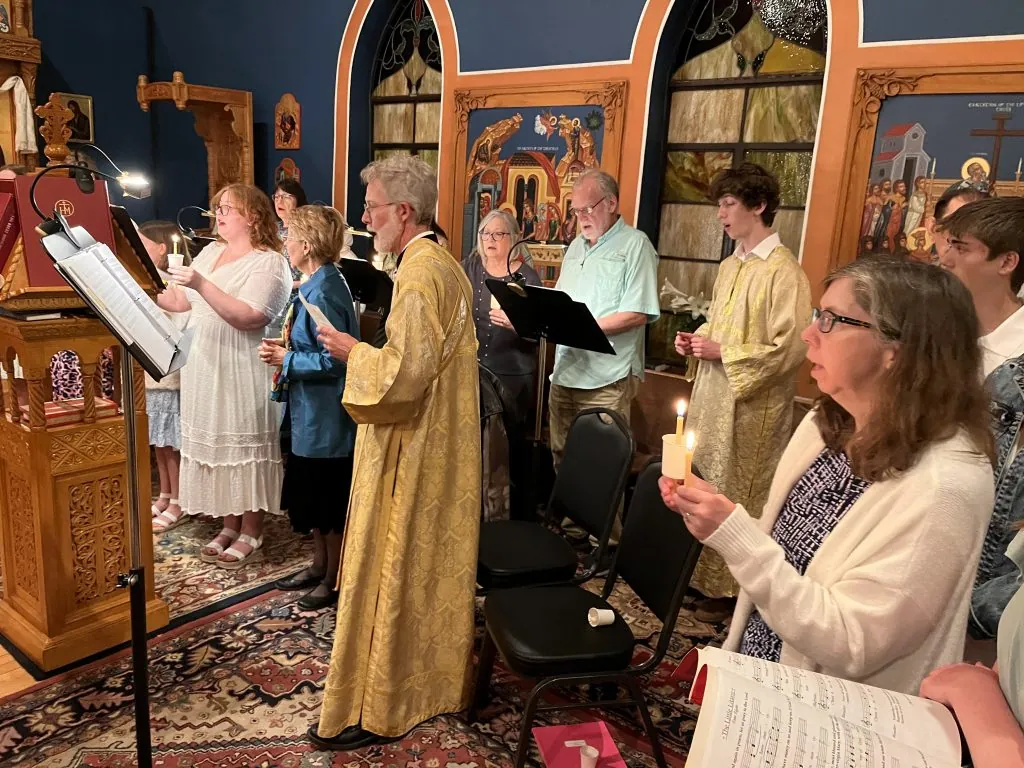 Subdeacon Max Murphy and parish choir members singing during worship
