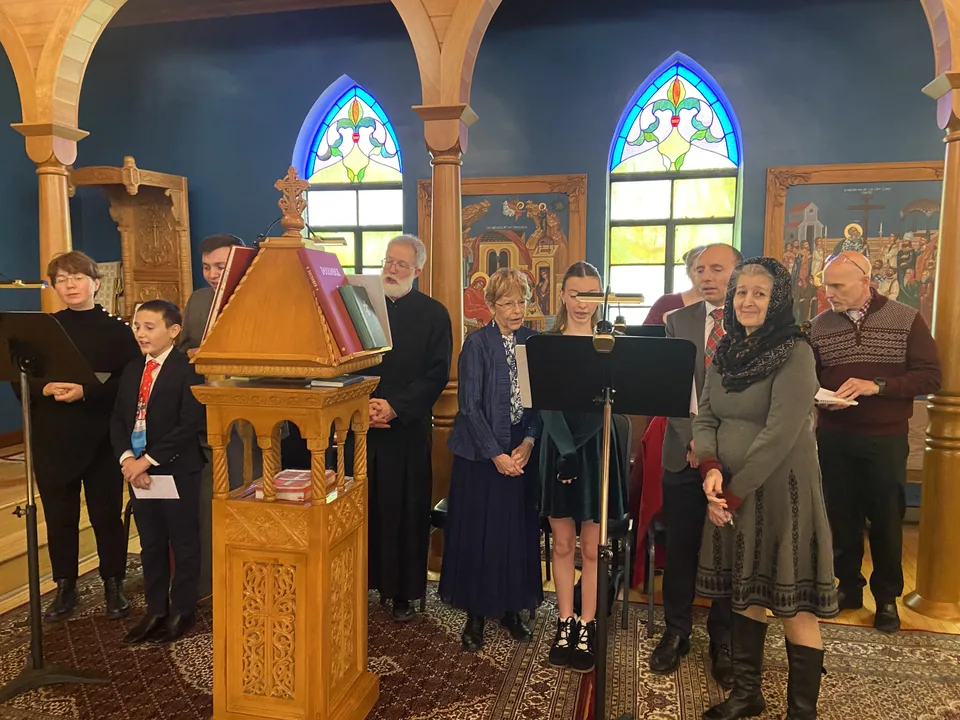 Parish choir members singing together around the wooden chant stand